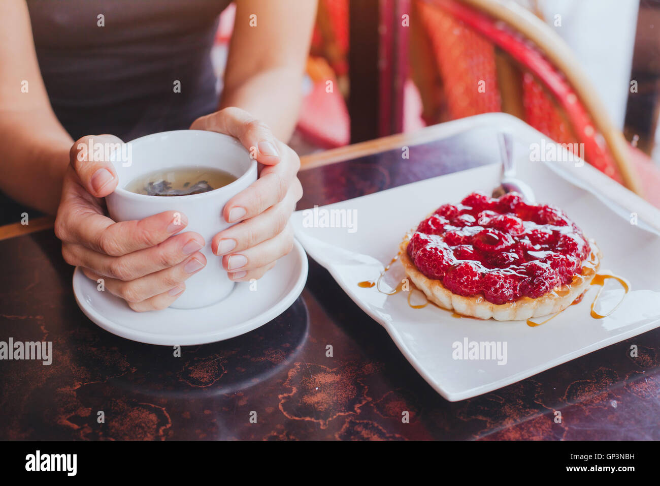 trinken Tee mit süßen Dessert, im Café, Nahaufnahme von Händen mit Cup und Obst Kuchen Stockfoto