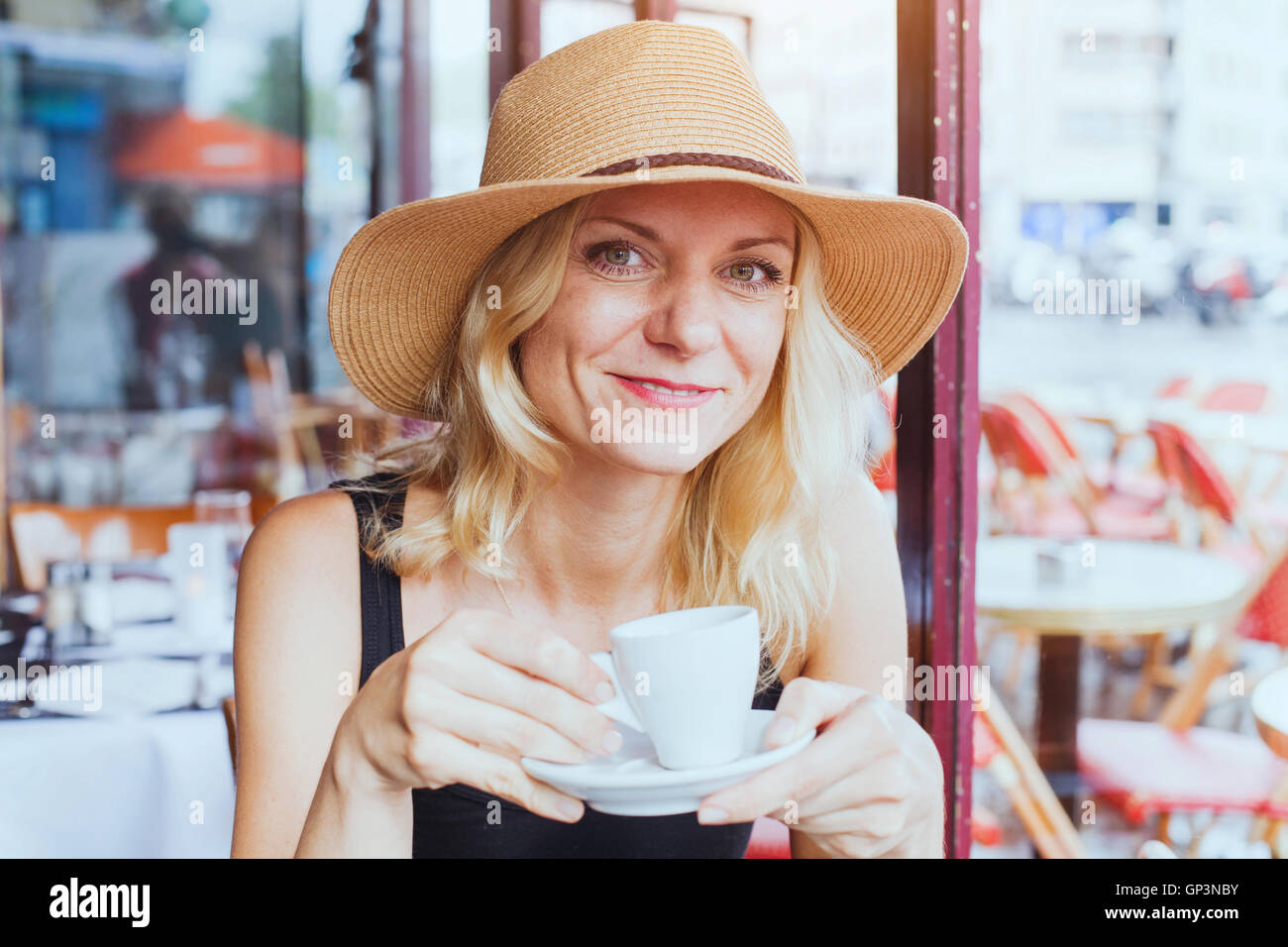 Porträt von Mode schöne mittlere gealterte Frau in Café mit Tasse Kaffee, glücklich, Lächeln und in die Kamera schaut Stockfoto