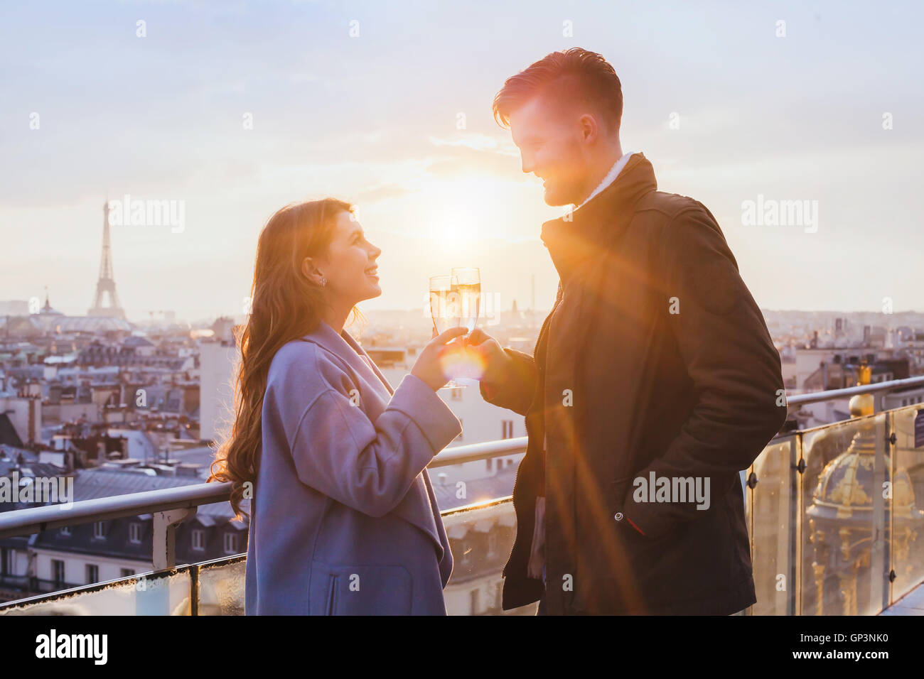 glückliches Paar Champagner trinken und lächelnd bei Sonnenuntergang in Paris, Feier Stockfoto