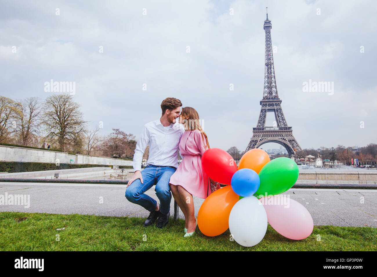 Fotoshooting, glückliches Paar mit Luftballons posiert in der Nähe von Eiffelturm in Paris Stockfoto