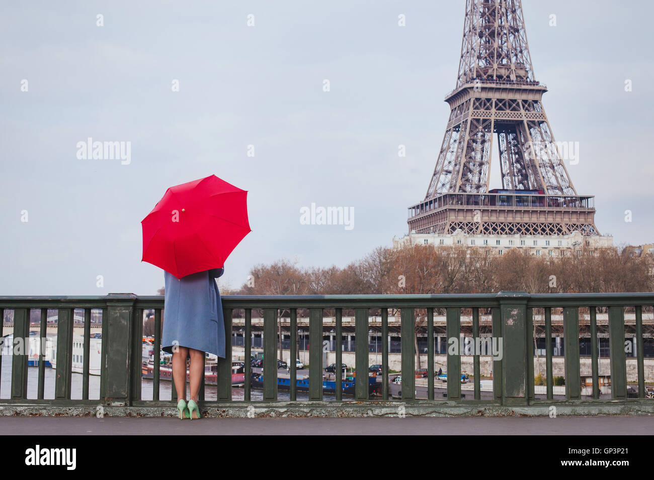 Frau mit roten Regenschirm stehen auf der Brücke mit Blick auf den Eiffelturm in Paris, Frankreich Stockfoto
