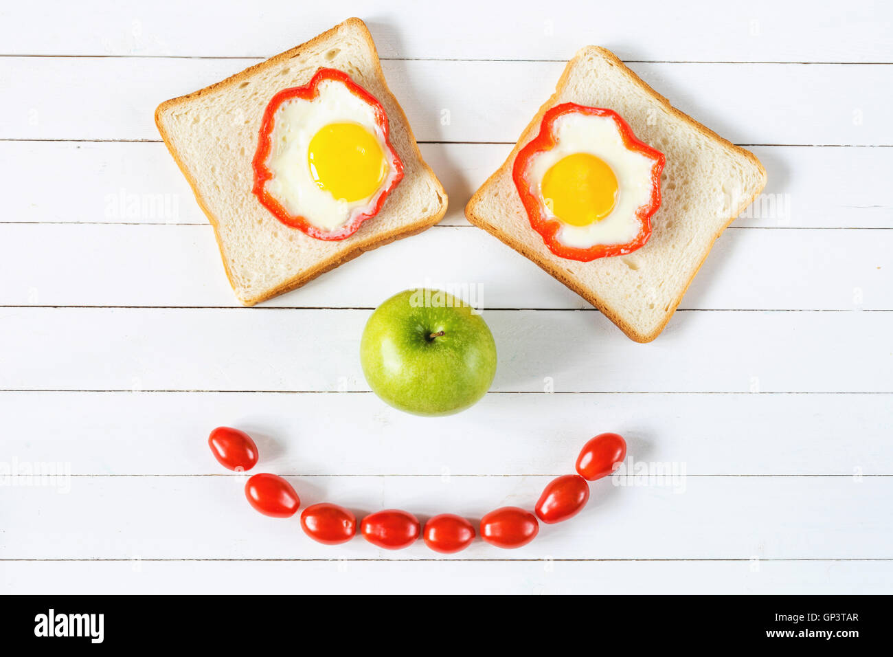 Smiley Essen. Frühstück-Food-Konzept, Ei-Sandwich, Apfel und Tomaten Stockfoto