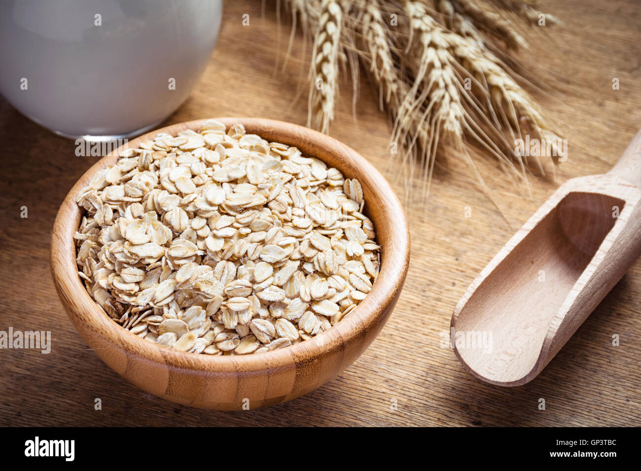 Haferflocken (Haferflocken), Milch und goldenen Weizenähren auf hölzernen Hintergrund. Rohkost-Zutaten, gesunde Lebensweise, Kochen Stockfoto