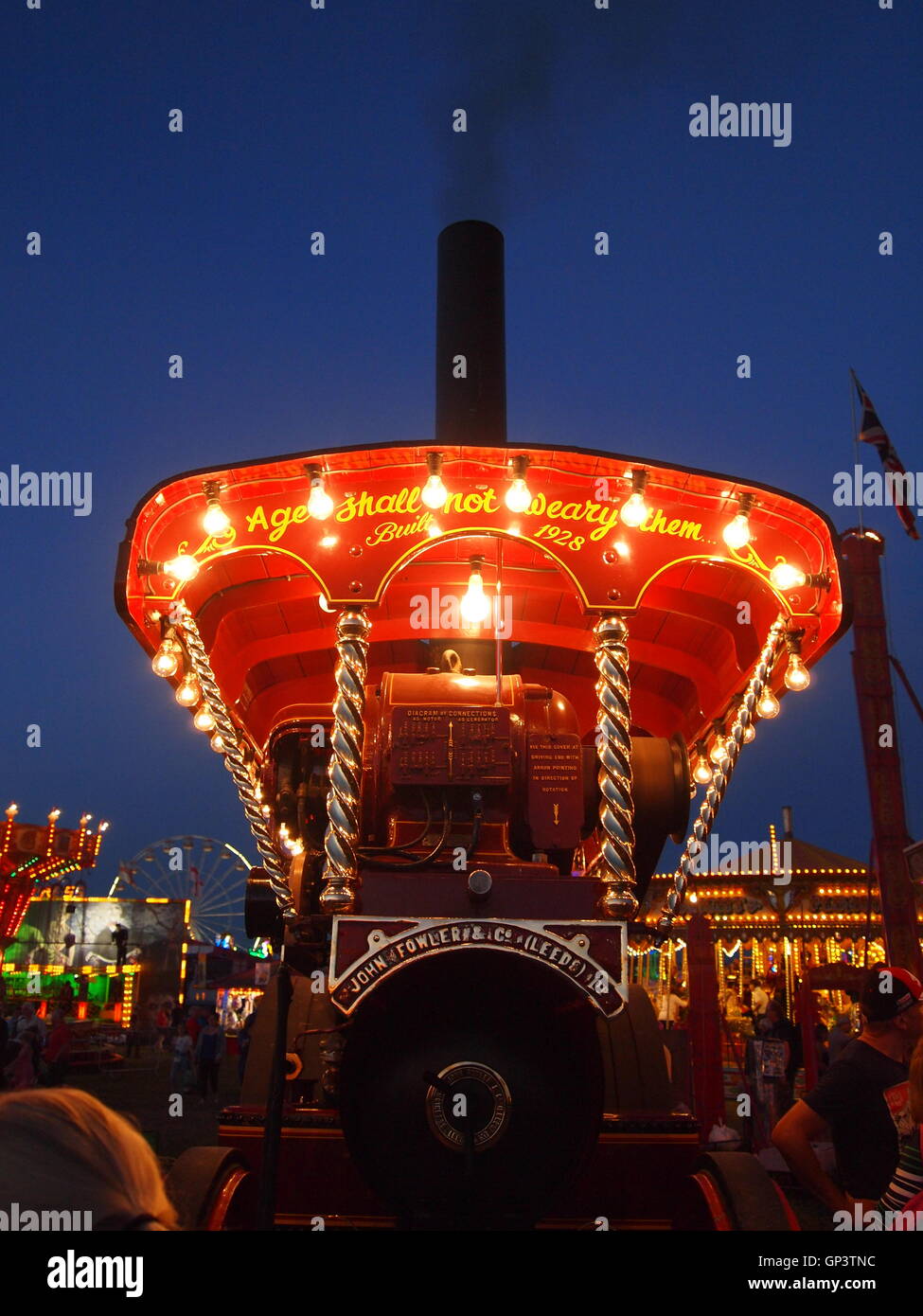 Dies ist die Vorderseite des einen Showmans Dampftraktor durch einen eigenen Generator und Glühbirnen, Kirmes im Hintergrund beleuchtet Stockfoto