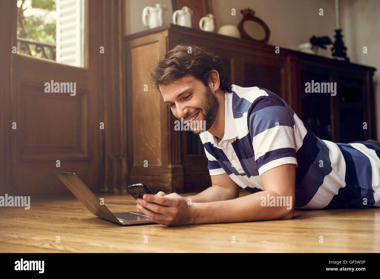 Mann liegt am Boden, die mit Laptop und smartphone Stockfoto