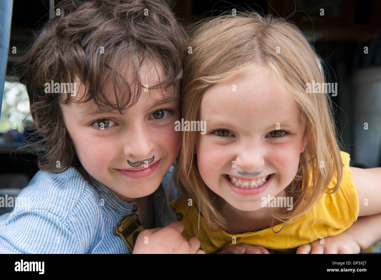 Junge Geschwister tragen gefälschte Schnurrbärte, Porträt Stockfoto