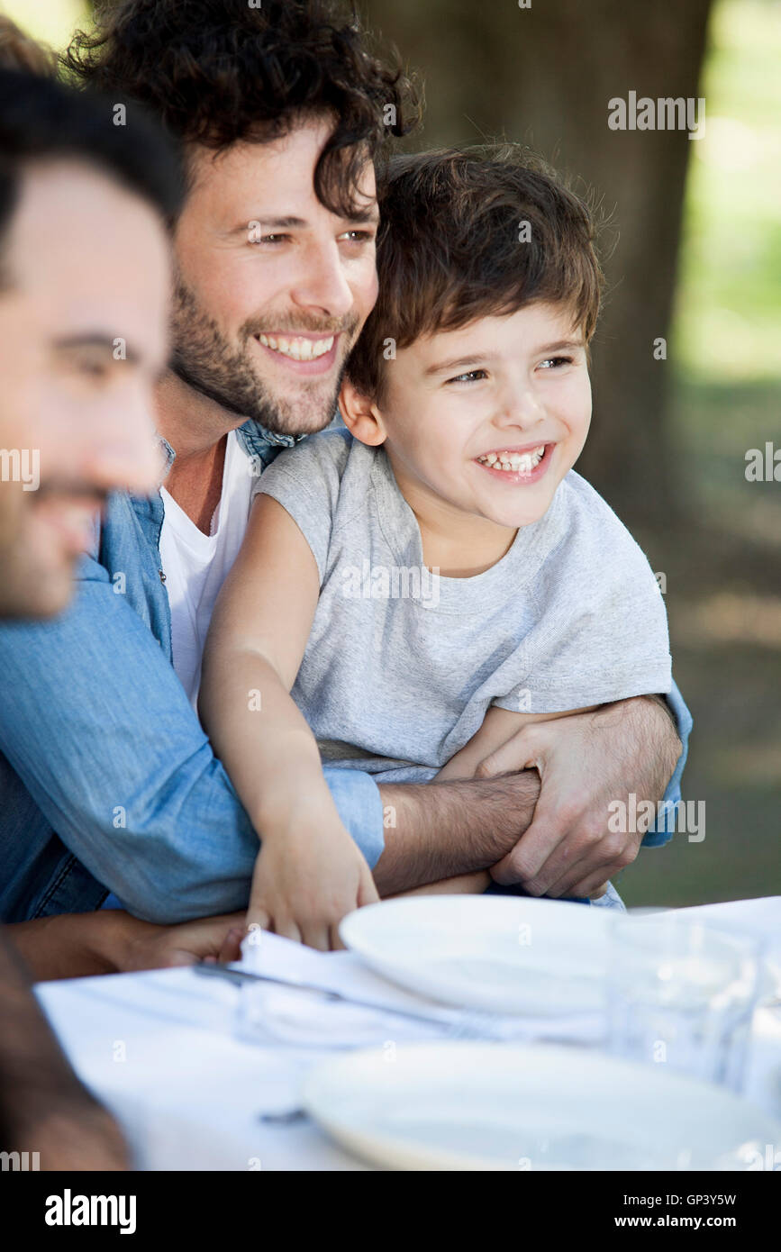 Vater und seinem kleinen Sohn mit Freunden bei Mahlzeit im freien Stockfoto