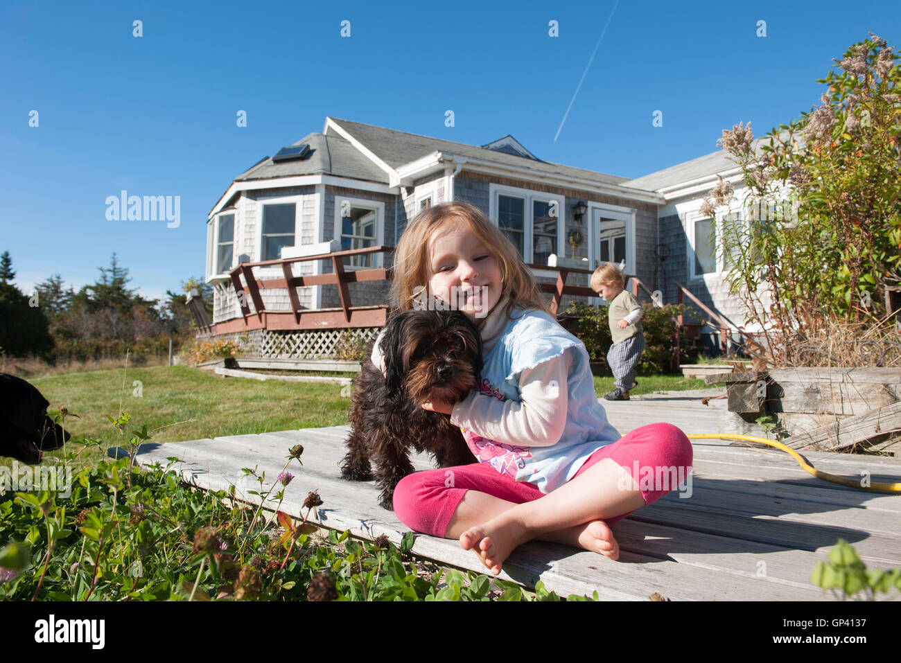 Kleines Mädchen sitzt auf dem Deck mit Hund Stockfoto