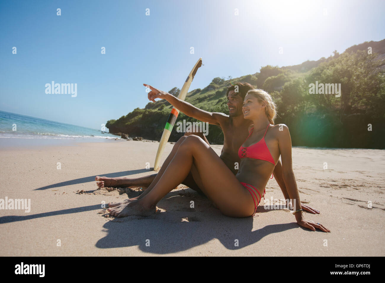 Seitenansicht Schuss junges Paar Entspannung am Ufer Meeres an einem Sommertag mit Mann zeigen etwas zu Frau in Richtung Meer. Y Stockfoto
