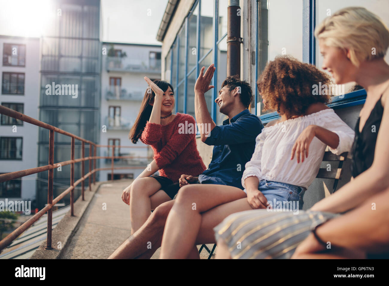 Gemischtrassigen Gruppe von Freunden Spaß in Balkon und geben hohe fünf. Junge Leute auf der Terrasse genießen. Stockfoto