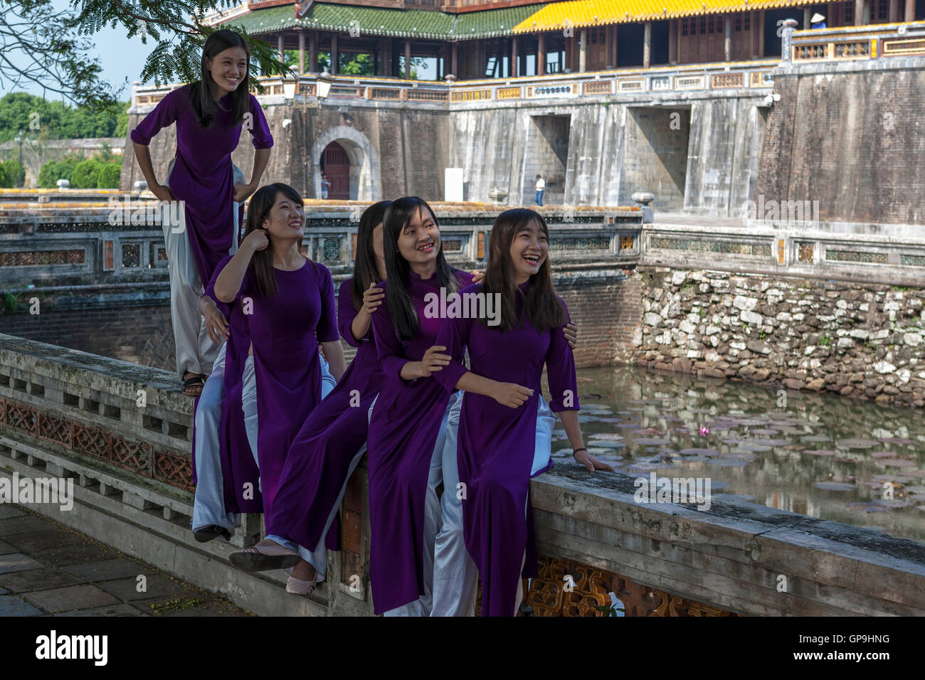 Glücklich, Lachen Studenten tragen traditionelle "Ao Dai" außerhalb der Ngo Mon Tor über die Kaiserstadt Hue, Vietnam Stockfoto