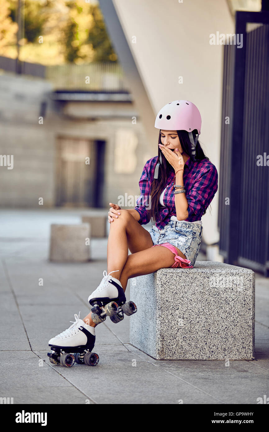 Mädchen traf ein Bein beim Rollschuhlaufen im städtischen Skatepark Stockfoto