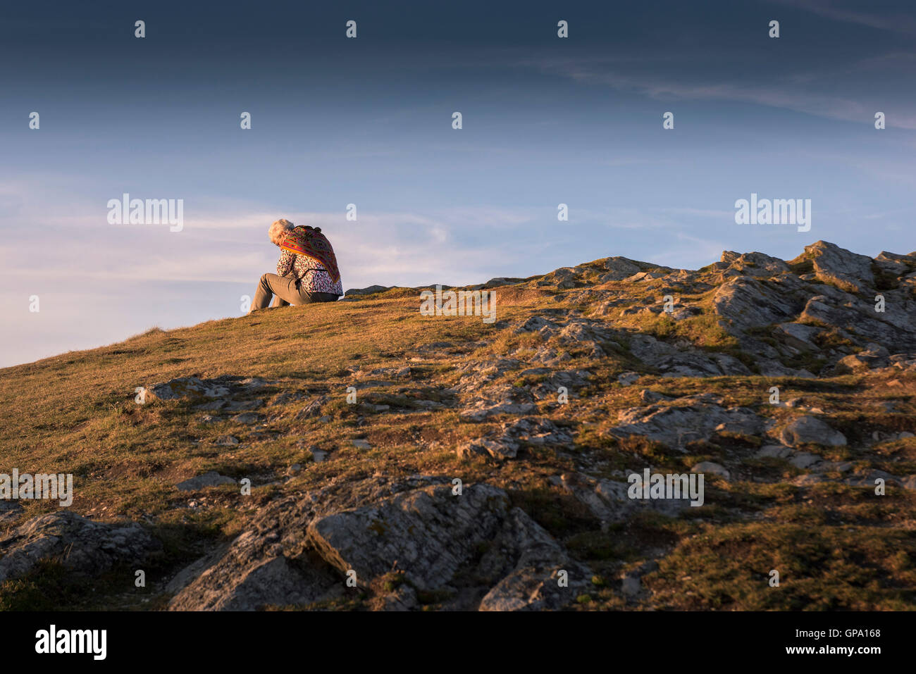 Eine Frau sitzt alleine auf Porth Insel in Newquay, Cornwall. Stockfoto