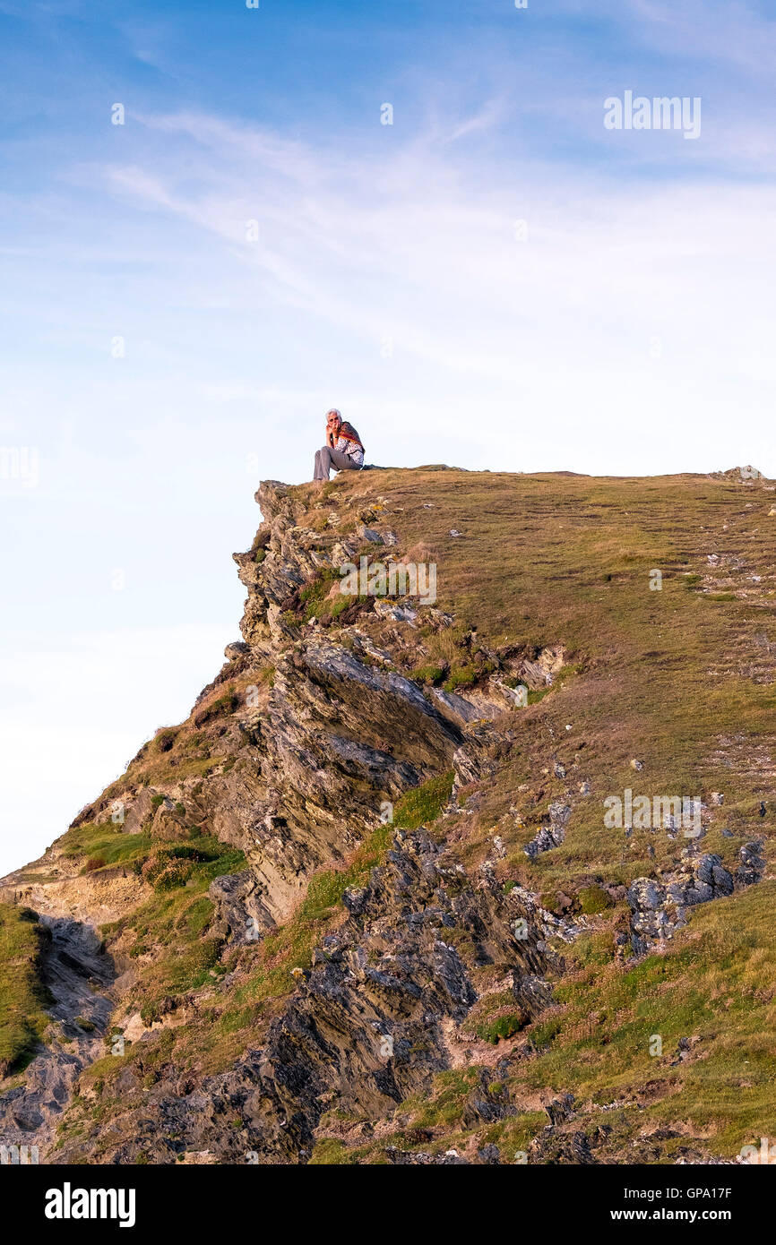 Eine Frau sitzt auf ihrem eigenen auf dem Gipfel des Trevelgue Head in Newquay, Cornwall. Stockfoto