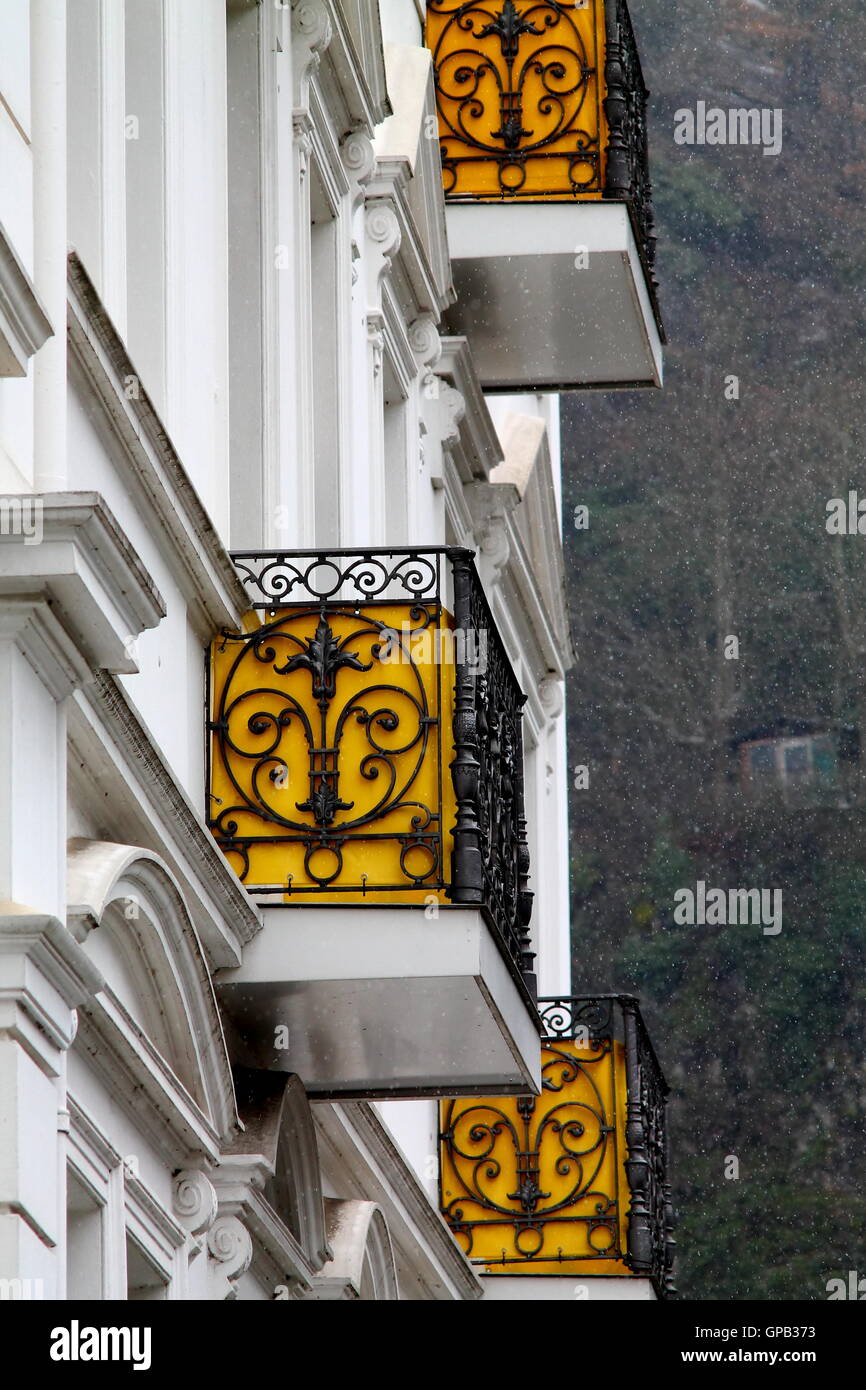 Alte Gebäude-Fragment mit gelben schmiedeeisernen Balkonen im Schnee. Stockfoto