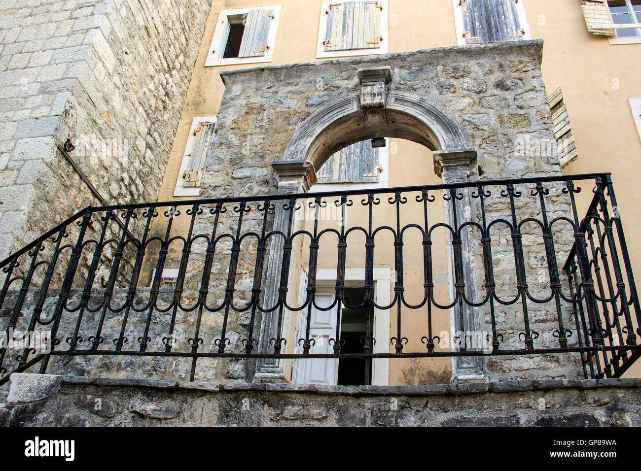 Alte Stadt von Budva, Montenegro - eine erhaltene Teil der mittelalterlichen Stadtmauer mit gewölbten Türen vor Gebäude aus dem 19. Jahrhundert Stockfoto