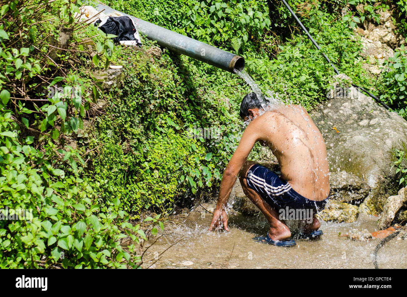 Man hockt unter Wasserpfeife selbst waschen Stockfoto