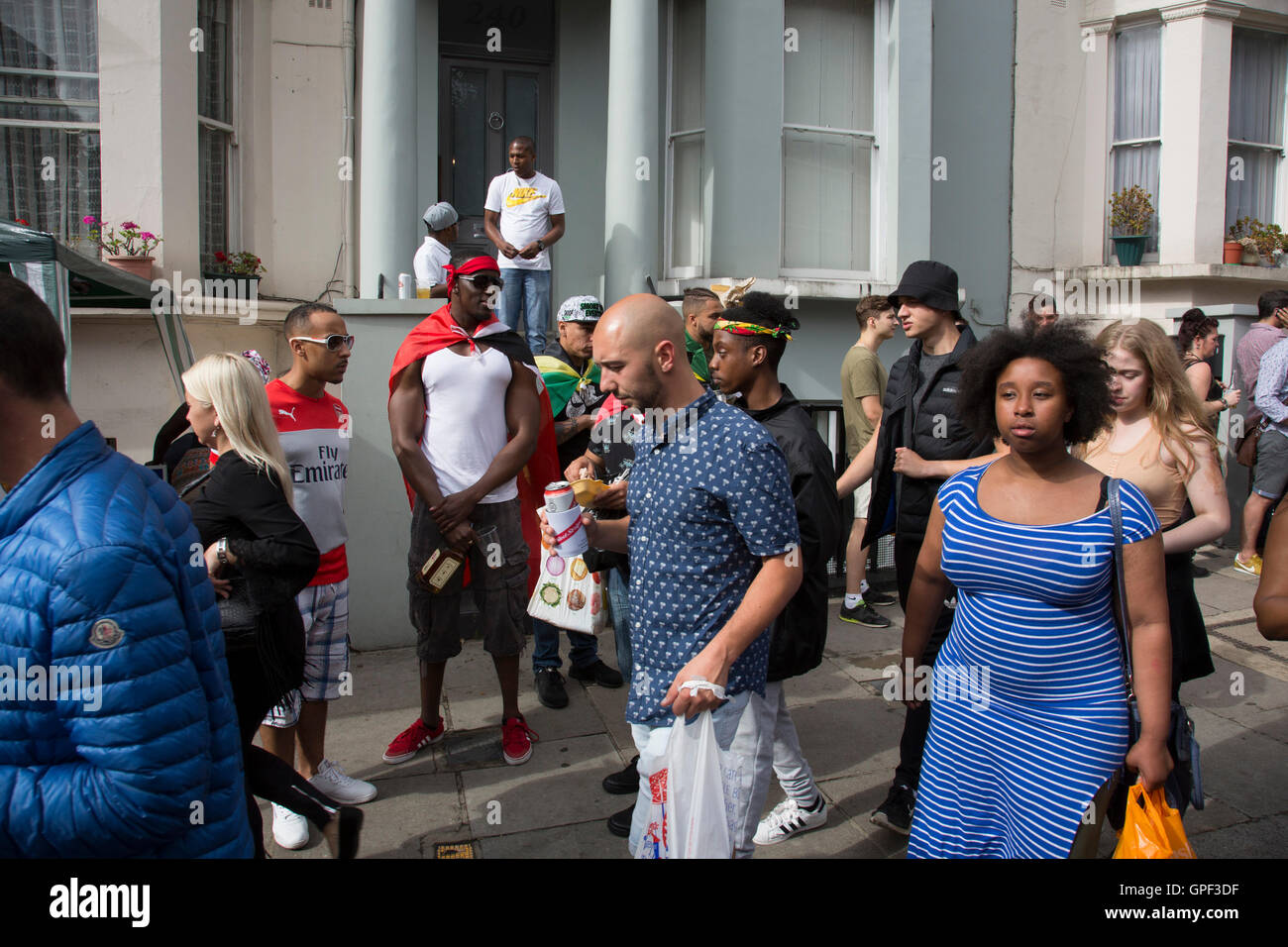 Menschen sammeln außen Residenzen am Ladbroke Grove auf Sonntag, 28. August 2016 bei den 50. Notting Hill Carnival in Westlondon. Ein Fest der Westindischen / Karibik Kultur und Europas größte Straßenparty, Festival und Parade. Nachtschwärmer kommen in hunderttausenden zum Spaß haben, tanzen, trinken und loslassen in die tolle Atmosphäre. Es wird geführt von den Mitgliedern der West-indischen / Karibische Gemeinschaft, besonders die Trinidad und Tobagonian britische Bevölkerung, von denen viele seit den 1950er Jahren in der Gegend gelebt haben. Der Karneval hat in der Vergangenheit und Zentren bis zu 2 Millionen Menschen angezogen. Stockfoto