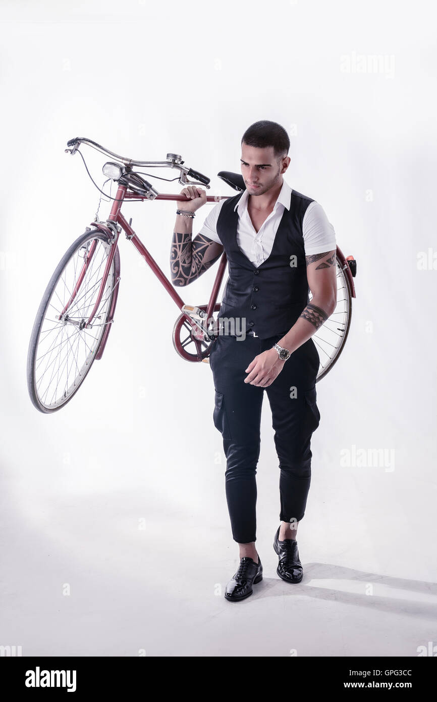 Porträt des jungen tätowierte Mann in elegante Kleidung mit einem Fahrrad. Studio gedreht. Ganzkörperfoto Stockfoto