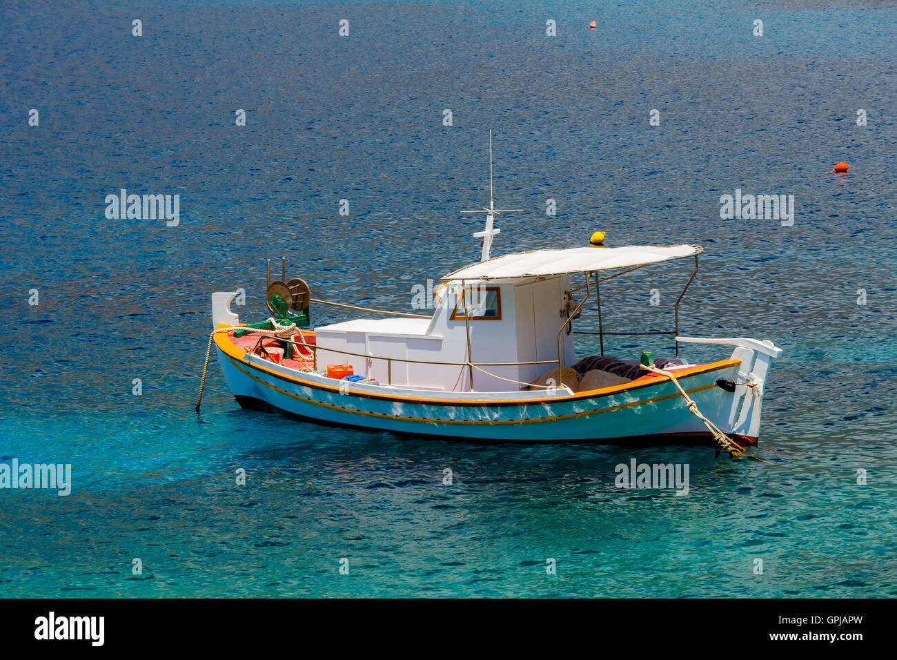 Traditionellen hölzernen Fischerboot schwimmt auf den bunten Gewässern am Nachmittag gegen den blauen Wassern des Limeni, Griechenland Stockfoto