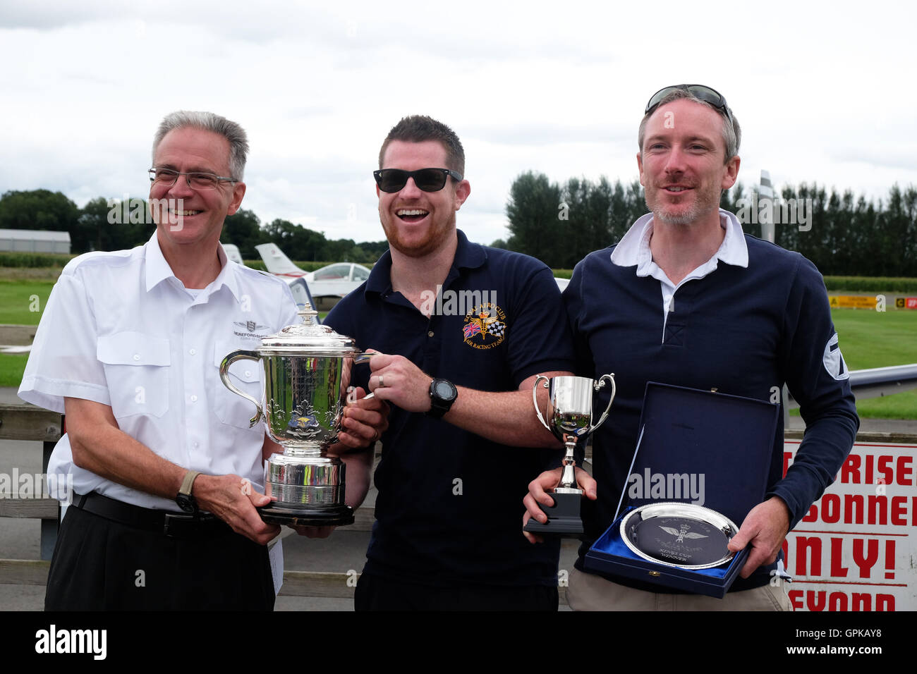 Shobdon Flugplatz, Herefordshire, UK - September 2016 - Dominic Crossan (Pilot im Zentrum) und Roger Scholes (Navigator rechts) erhalten die Copa del Rey von Marcus Woof (links) Herefordshire-Aero-Club. Des Königs Cup Luftrennen ist im Besitz der Royal Aero Club und arbeitet auf einer Handicap-Basis mit einer Vielzahl von Flugzeugen des Typs Rennen rund um Pylonen, findet in diesem Jahr am Shobdon Flugplatz. Des Königs Cup Luftrennen wurde initiiert von König George V und 1922 zum ersten Mal statt. Stockfoto