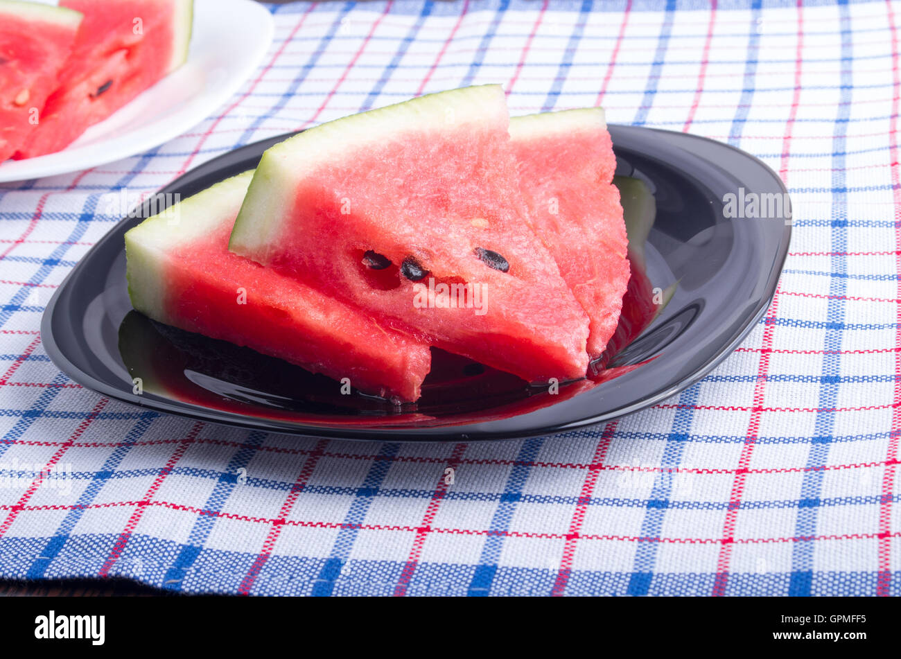 Seitenansicht der saftige rote Wassermelone Stücke auf einer schwarzen Platte auf eine Tischdecke Stoff mit flachen Schärfentiefe gemacht Stockfoto