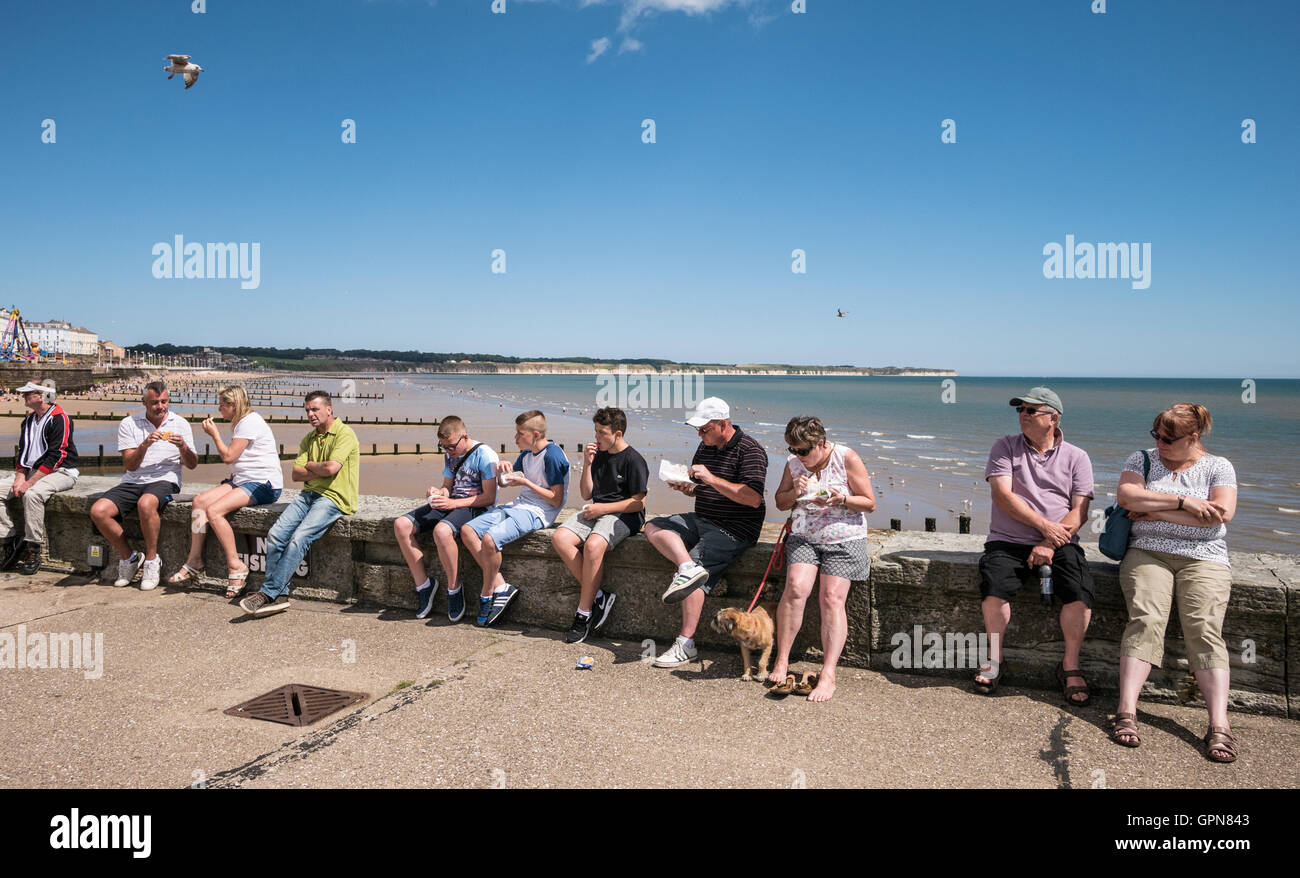 Touristen sitzen am Deich Bridlington East Yorkshire UK Stockfoto