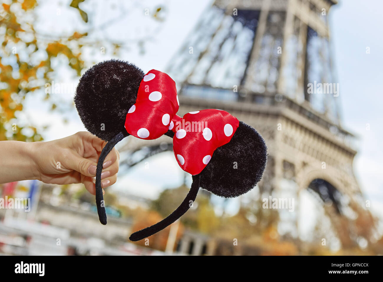 Perfekte Herbstferien in Disneyland und Paris. Closeup auf Minnie Mouse- Ohren in weiblicher Hand am Ufer in der Nähe von Eiffelturm Stockfotografie  - Alamy