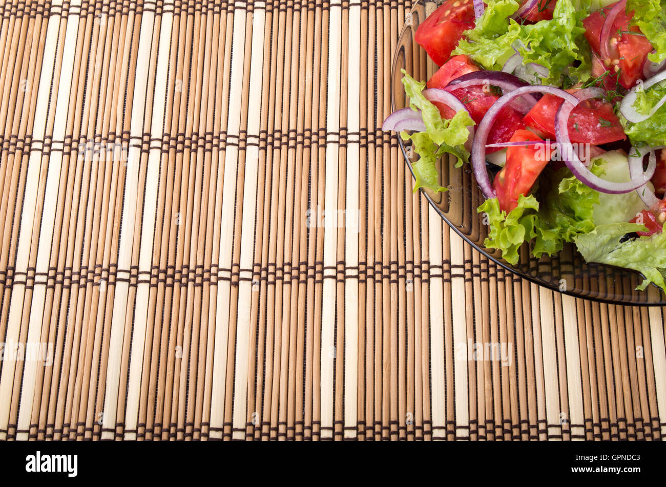 Hintergrund für Lebensmittel Styling einer transparenten Platte frische vegetarische Salat von rohem Gemüse und Bambusmatte Stockfoto