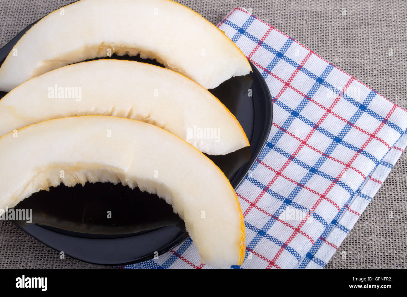 Gesunde und nützliche Dessert süße Gelbe Melone Scheiben auf einer schwarzen Platte auf Tischdecke Hintergrund Stockfoto