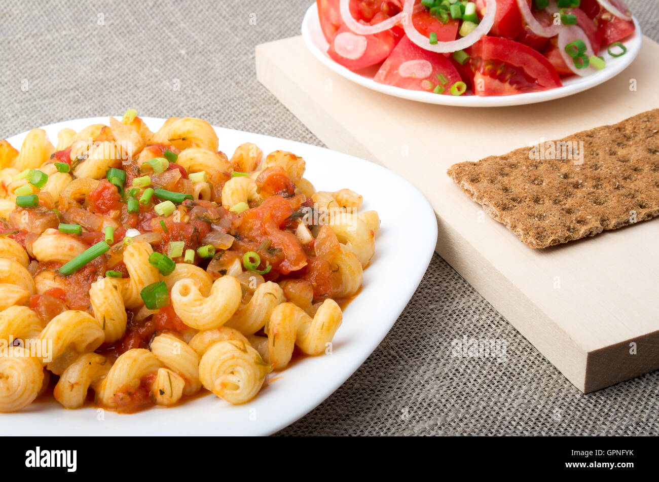 CAVATAPPI Nudeln mit Sauce aus gedünstetem Gemüse serviert mit einem Salat aus rohen Tomaten und Roggen Cracker Stockfoto