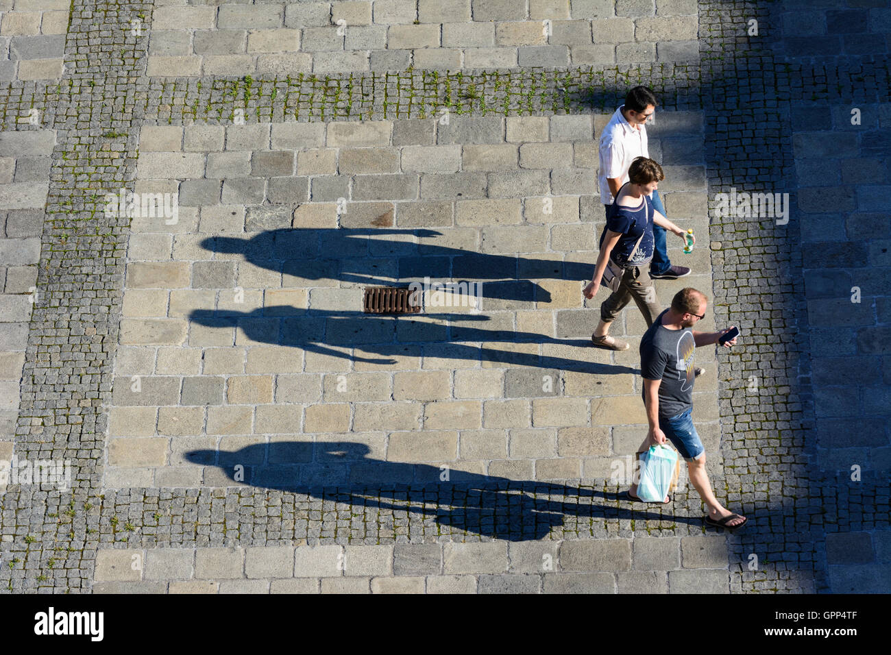 3 Personen gehen auf Asphalt, lange Schatten in Linz, Oberösterreich, Oberösterreich, Österreich Stockfoto