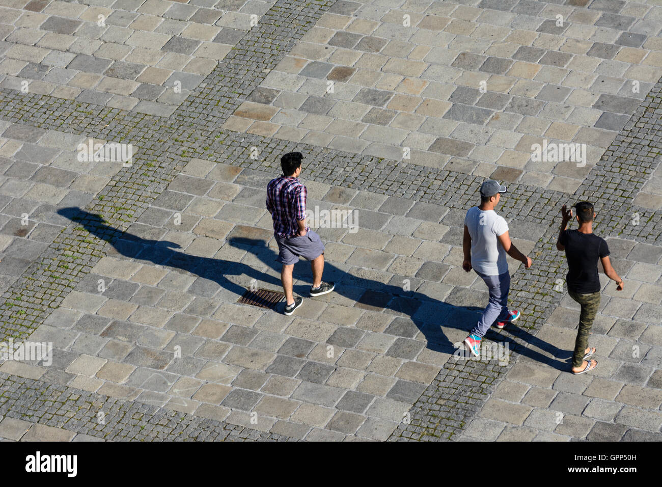 3 Personen gehen auf Asphalt, lange Schatten in Linz, Oberösterreich, Oberösterreich, Österreich Stockfoto