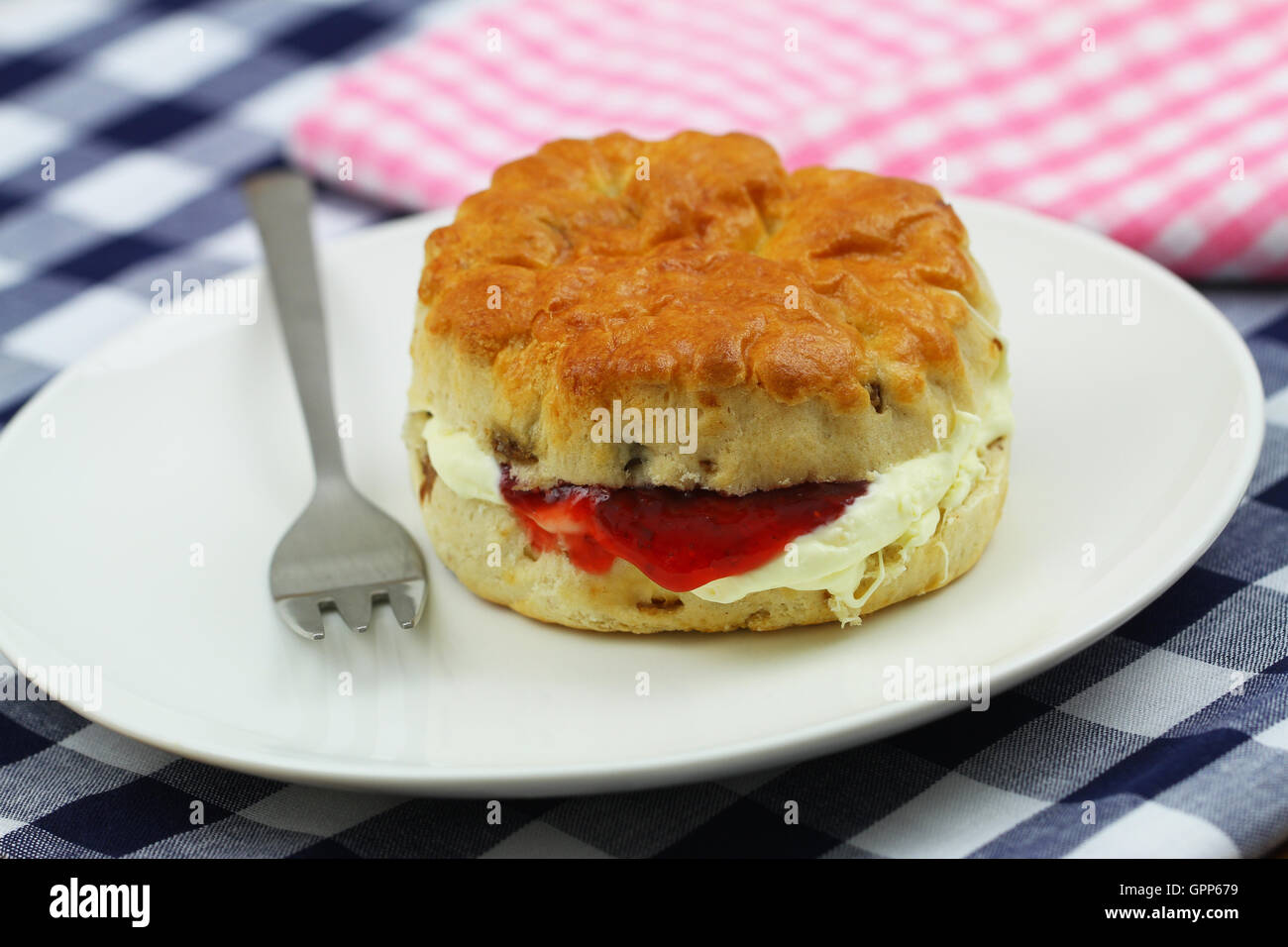 Frisch gebackenen englischen Scone mit traditionellen Clotted Cream und Erdbeermarmelade auf weißen Teller Stockfoto