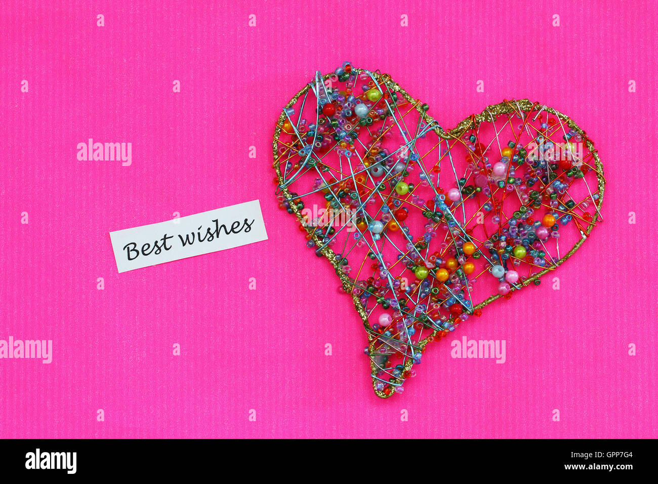 Die besten Wünsche Karte mit Herz gemacht von bunten Perlen auf rosa Hintergrund Stockfoto