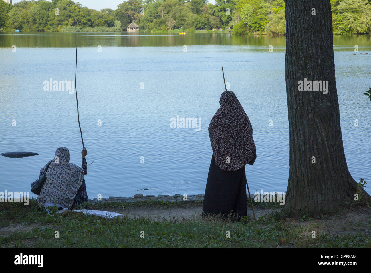 Zugewanderten muslimischen Frauen Fische im See am Prospect Park, Brooklyn, NY. Stockfoto