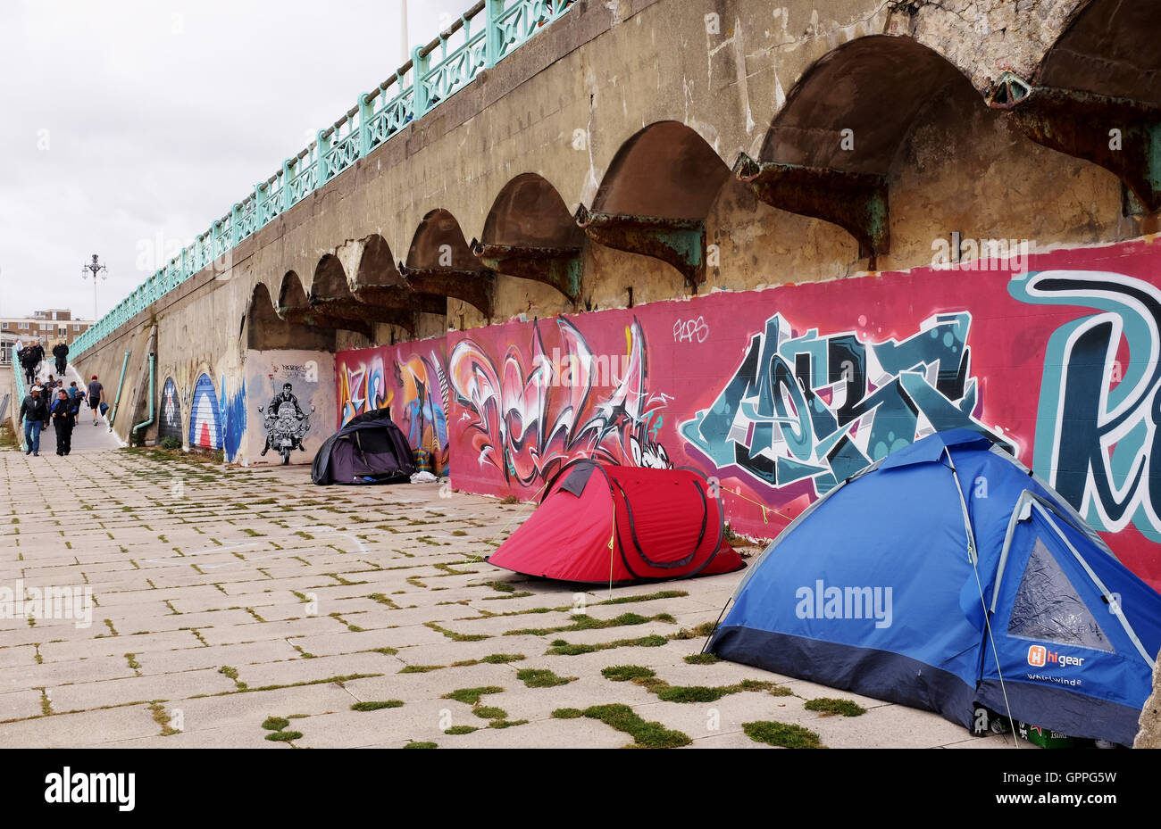 Tribut-Graffiti-Kunst zu einem Mod auf einem Roller durch Künstler Jef Aerosol entlang der Bögen auf Brighton Seafront mit Obdachlosen Zelte Stockfoto