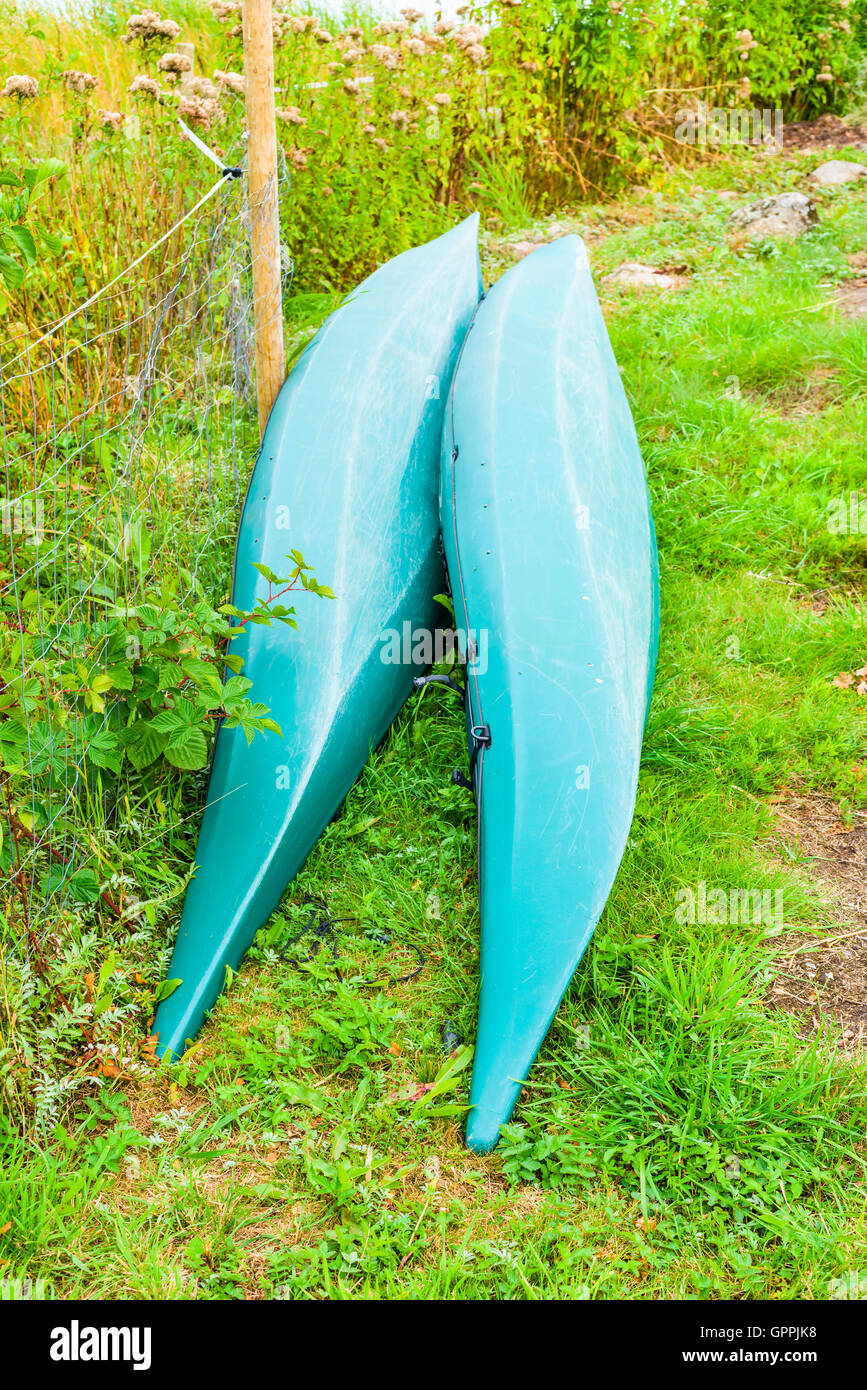 Zwei Kopf Kunststoff Kanus oder Kajaks auf dem trockenen. Die Kanus sind grün und Lauge neben einer saldierten Zaun neben einer schmalen walkwa Stockfoto
