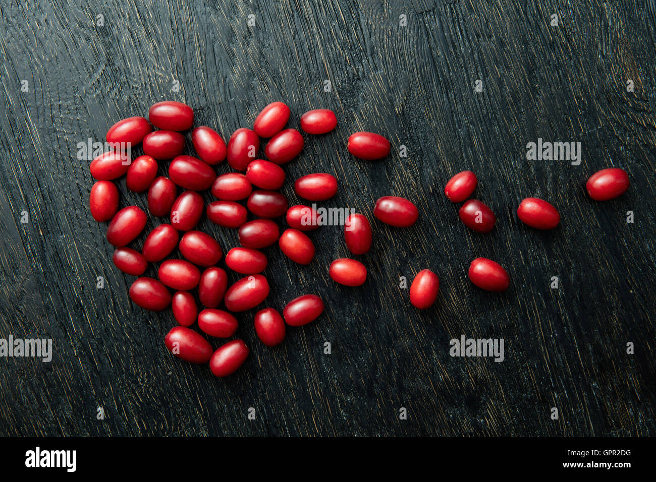 Roter Hartriegel Beeren als ein gebrochenes Herzform auf schwarzem Hintergrund aus Holz Stockfoto