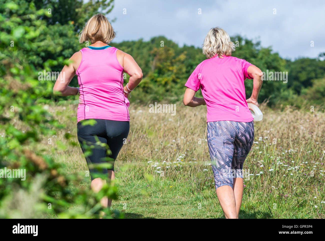 Gesunde Lebensweise. Paar der weiblichen Jogger Joggen durch die Felder in der britischen Landschaft. Stockfoto