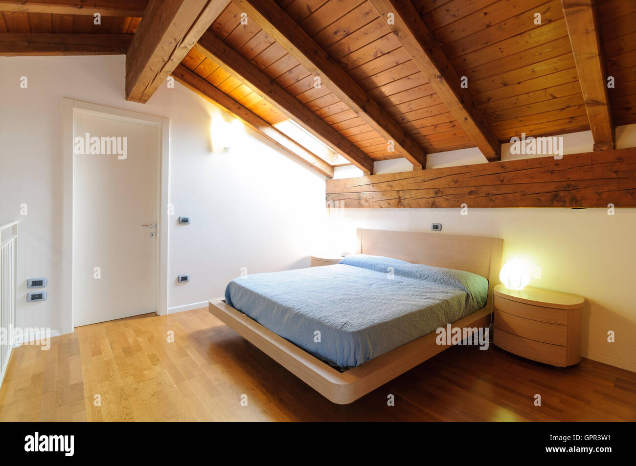 Gemütlichen Dachboden Schlafzimmer mit Holzboden und Decke mit sichtbaren Balken Stockfoto