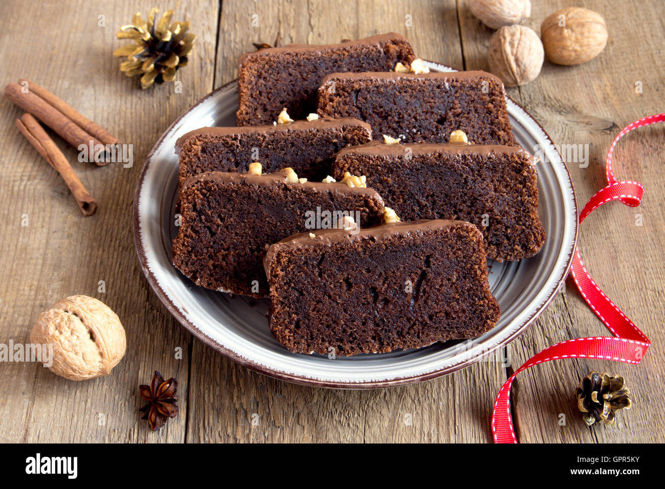 In Scheiben geschnittene Schokoladenkuchen mit Nüssen und Gewürzen zu Weihnachten über rustikale Holz Hintergrund Stockfoto
