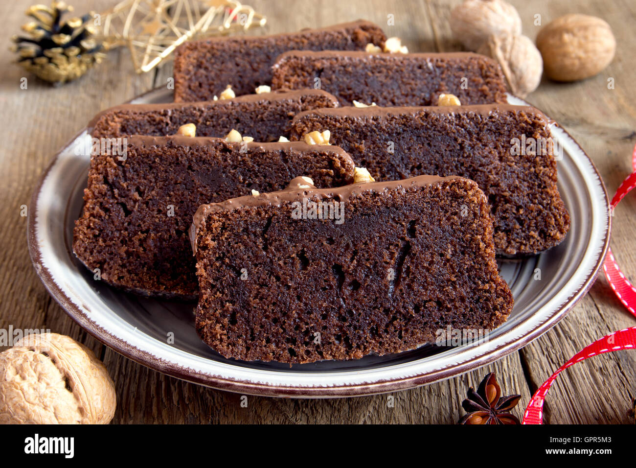 In Scheiben geschnittene Schokoladenkuchen mit Nüssen und Gewürzen zu Weihnachten über rustikale Holz Hintergrund Stockfoto
