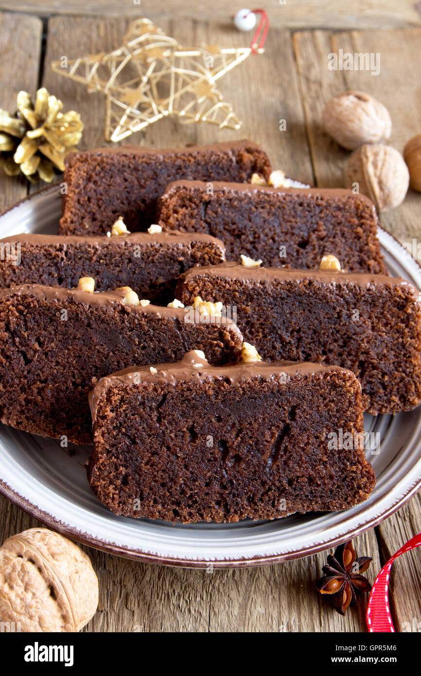 In Scheiben geschnittene Schokoladenkuchen mit Nüssen und Gewürzen zu Weihnachten über rustikale Holz Hintergrund Stockfoto