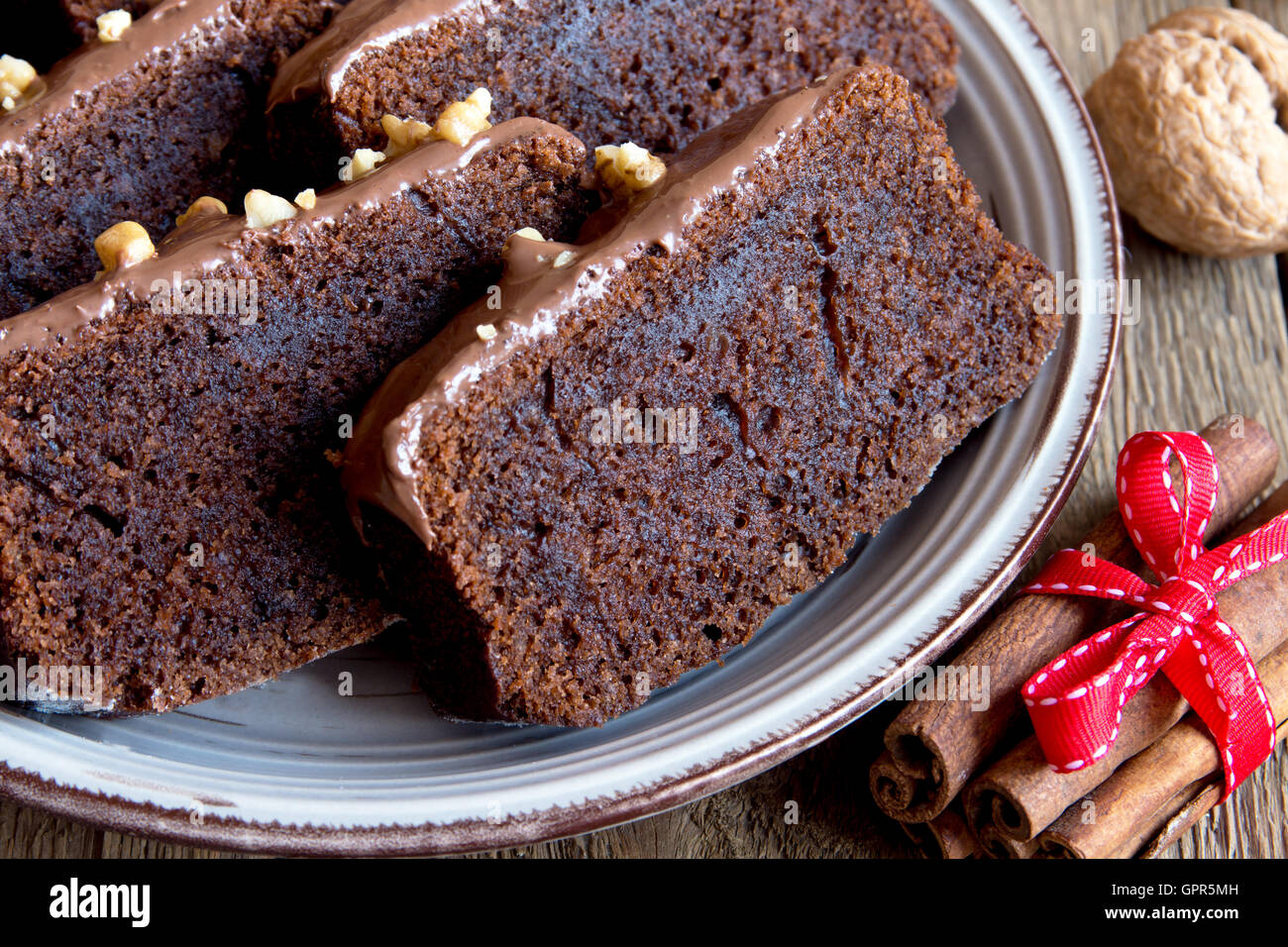 In Scheiben geschnittene Schokoladenkuchen mit Nüssen und Gewürzen zu Weihnachten über rustikale Holz Hintergrund Stockfoto