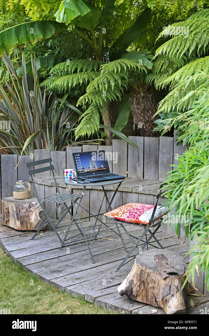 Arbeiten von zu Hause aus: ein Laptop-Computer, Smartphone und Kaffeetasse auf einem Gartentisch in einem städtischen, UK-Garten an einem Sommertag. Stockfoto