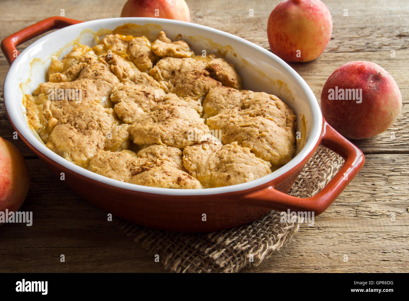 Hausgemachte Pfirsich Schuster (Streusel) in die Auflaufform über rustikale Holz Hintergrund Stockfoto
