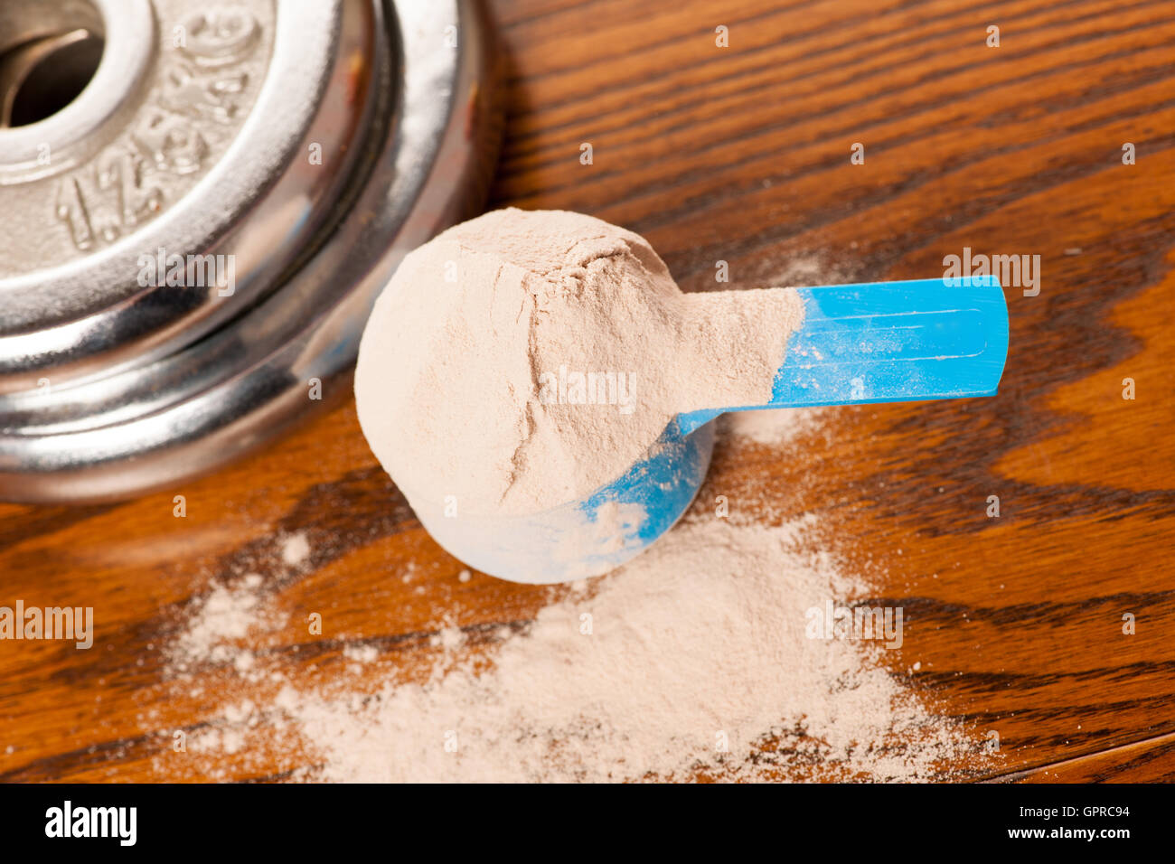 Molke-Protein-Pulver bei der Messung der Schaufel und Hantel auf hölzernen Hintergrund. Stockfoto