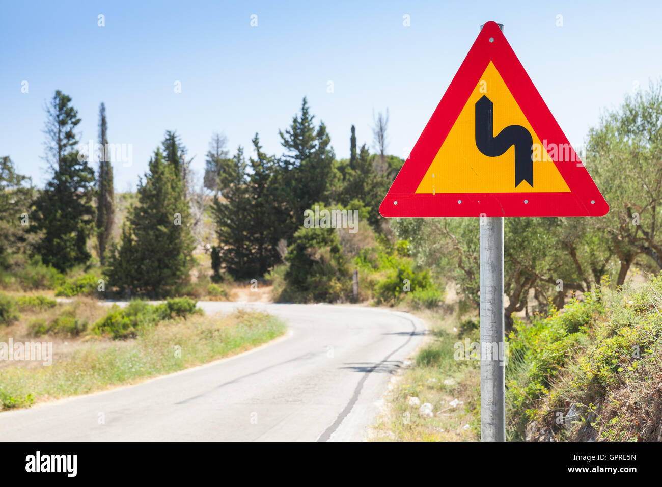 Doppelte Biegung gebogen dreieckigen gelben Warnung Roadsign mit rotem Rand und schwarzer Pfeil Stockfoto