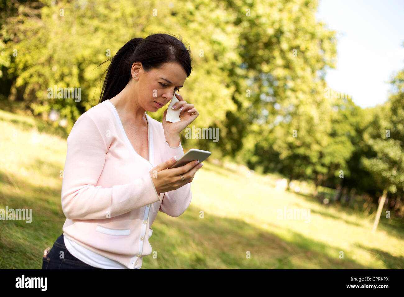 Trauriges Mädchen wischte sich eine Träne während des Lesens einer SMS-Nachricht Stockfoto